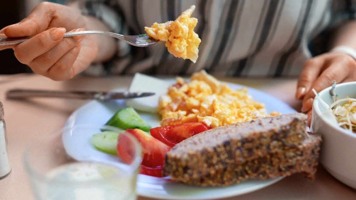 Eating breakfast with scrambled eggs on fork