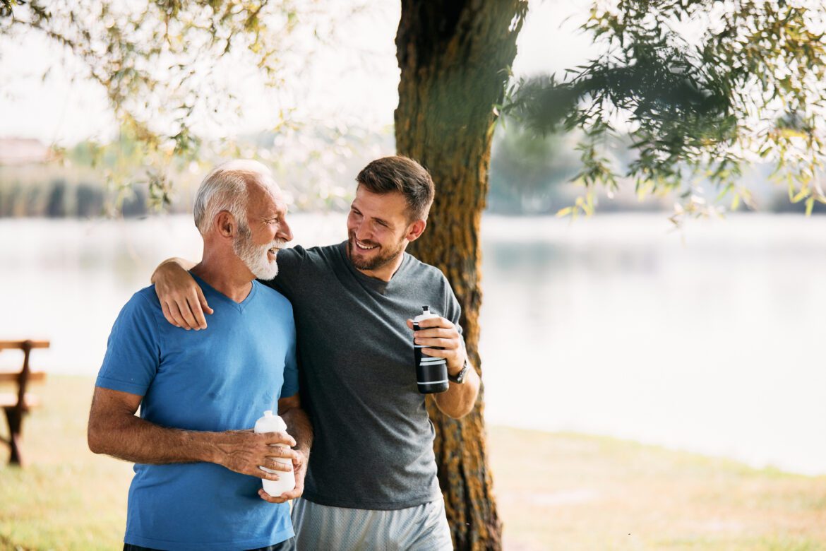 Happy senior athlete and his son talking during their water break in nature.