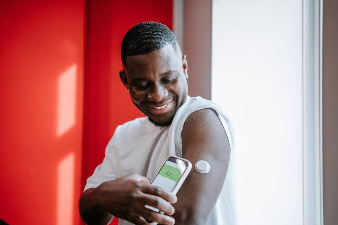 Diabetes blood sugar check. Smiling interracial man using smart glucose tracker with smartphone app
