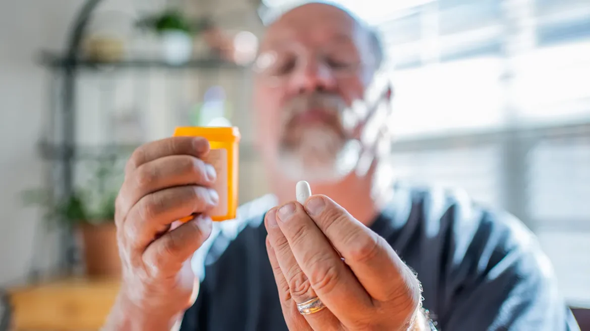 Senior man holds pill bottle
