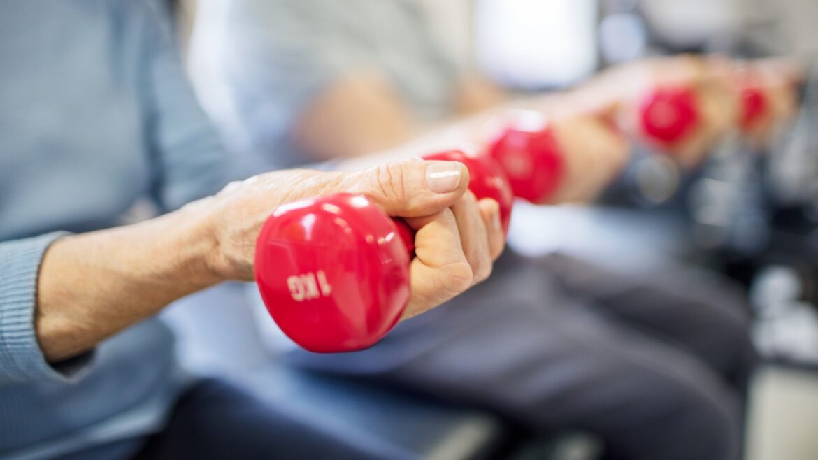Midsection of senior woman lifting dumbbells