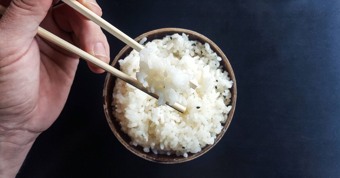 0 Hand taking some white rice with chopsticks