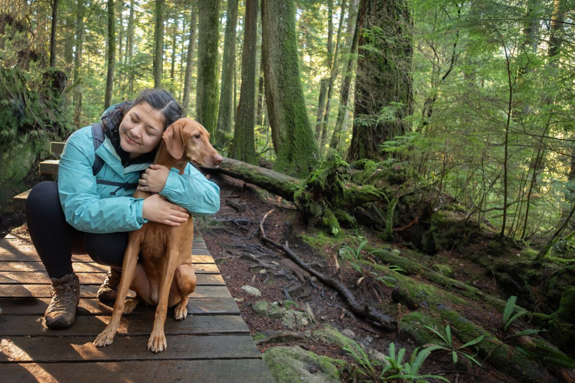 Multi Ethnic Teenaged Girl Hugging Her Dog on Forest Trail